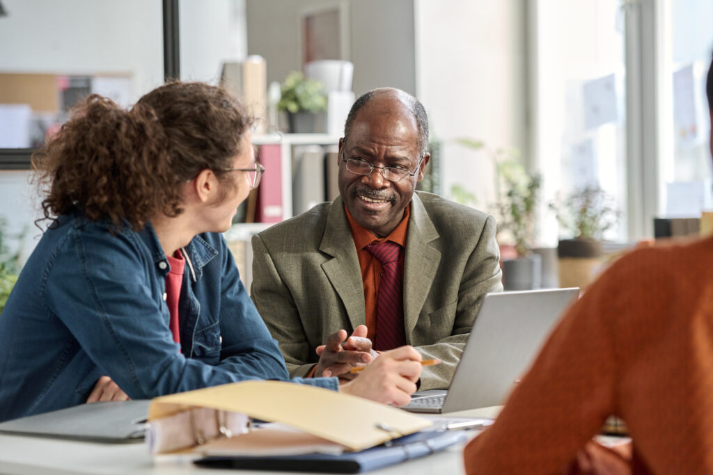 smiling senior businessman talking to young coworker